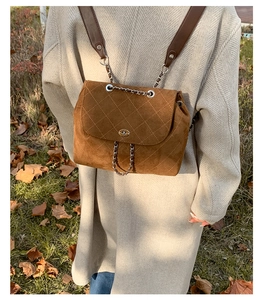 Detail of brown quilted suede backpack with chain straps and metal twist lock