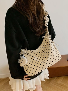 Chic cream polka dot dumpling shoulder bag with ruffled strap and cute plush charm