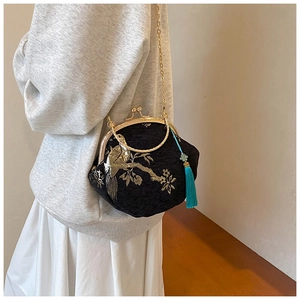 Detail of embroidered bird floral pattern on black velvet crossbody bag with chain