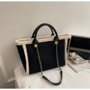 Detail of winter suede tote bag with white faux fur trim and gold metal chain strap