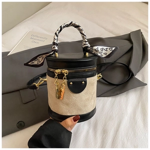 Close-up of quilted bucket bag featuring a silk scarf handle on white bedding