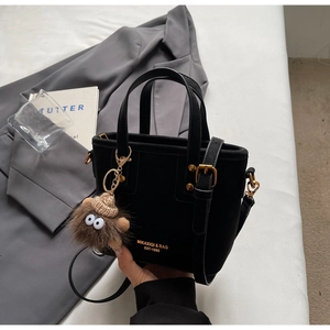Detail of black suede Boston bag with vintage gold hardware and plush monster charm