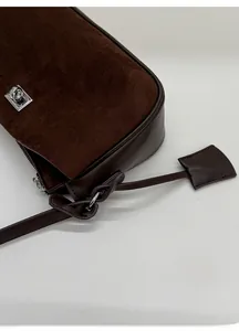 Detail of chocolate brown suede and smooth leather bag with silver metal twist lock