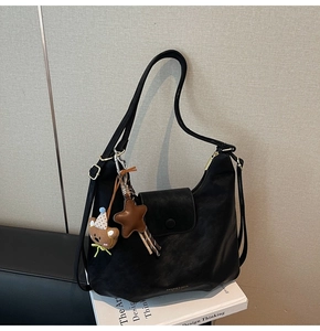 Détail d'un sac hobo en similicuir noir avec breloque ours en peluche et étoile