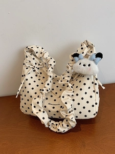 Chic cream polka dot dumpling bag with ruffled shoulder strap and plush puppy charm