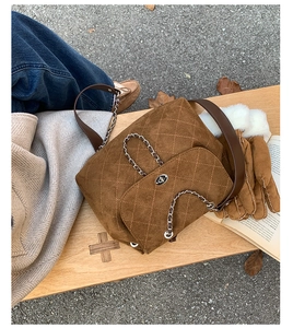 Detail of caramel suede quilted bucket bag with silver chain and metal turn-lock closure