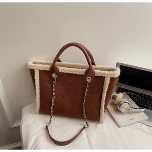 Brown suede tote bag with white faux fur trim and gold chain strap in office setting