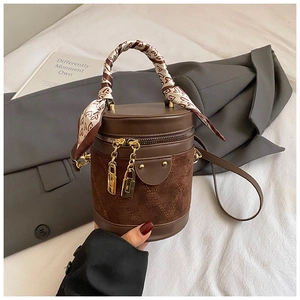 Detail of coffee brown cylinder bucket bag with quilted patterns and silk scarf handle