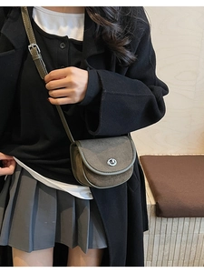 Detailed view of women's matte leather saddle bag worn cross-body in a minimal setting