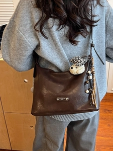 Vintage brown leather shoulder bag with leopard dog charm and wooden bead tassel