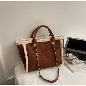 Close-up of brown suede tote bag with faux shearling trim and stylish metal chain strap
