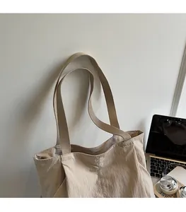 Detail of a beige nylon tote bag showing wide shoulder strap and waterproof fabric texture