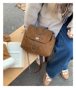 Brown quilted suede backpack with silver twist lock and chain detail on wooden bench