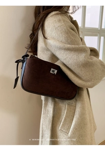 Detail of retro dark brown suede shoulder bag with silver metal swivel lock on beige coat