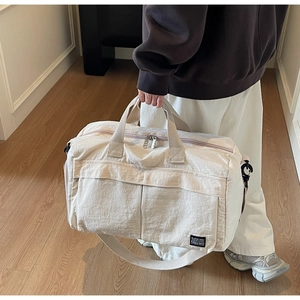 Close-up of cream white travel bag with multiple pockets and adjustable shoulder strap