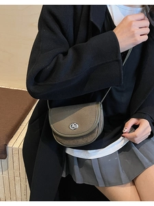 Detailed view of an olive green saddle bag featuring a matte finish and silver metal lock