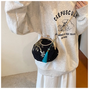Detail of embroidered floral patterns on black satin shell bag with long blue tassel