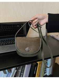 Detail of olive green suede saddle bag featuring silver metal twist lock and matte texture
