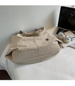 Large khaki tote bag with pleated nylon fabric and laptop accessories on a desk