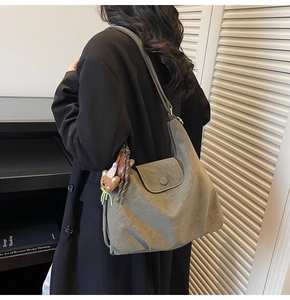 Sac hobo vert olive avec charm ours porté à l'épaule pour un look décontracté chic