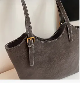 Détail du sac cabas gris-brun foncé montrant les surpiqûres blanches et la boucle dorée