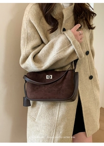 Detail of dark brown suede shoulder bag with silver turn-lock on beige coat