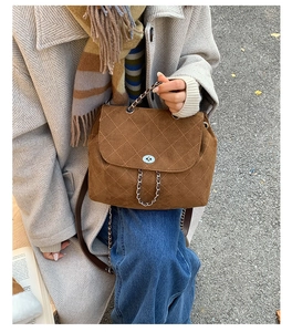 Detail of brown quilted suede bucket bag with silver turn-lock and metal chain handle