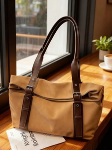 Sac fourre-tout kaki grande capacité avec anses marron foncé sur un rebord de café