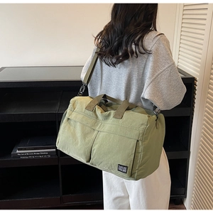 Model wearing a sage green travel bag with side pockets and adjustable shoulder strap