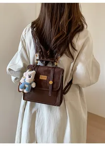 Brown retro leather backpack with golden metal logo plate and cute white bear keychain