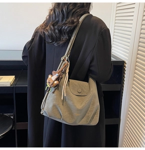 Vue d'épaule du sac fourre-tout vert olive en cuir mat avec un charme d'ours peluche
