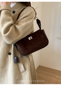Detail of dark brown suede shoulder bag with silver turn-lock and leather trim