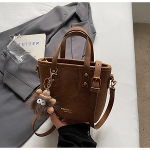 Close-up of brown frosted leather tote bag with monster charm and golden hardware detail