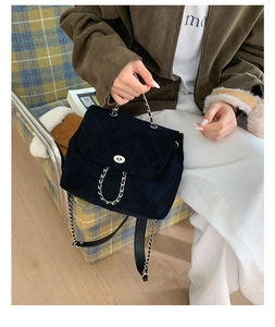 Detail of black quilted suede backpack featuring a silver twist lock and chain strap