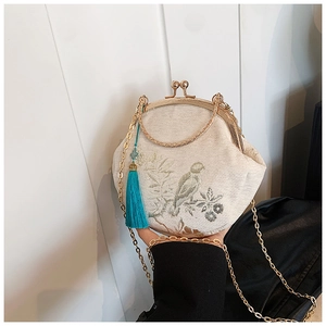 Detail of embroidered floral pattern on shell bag with retro metal clasp and tassel