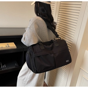 Detail of black nylon fitness bag with front zipper pocket and shoulder strap shown in use
