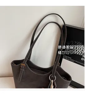 Détail d'un grand sac cabas en daim marron avec coutures fines et boucles métalliques