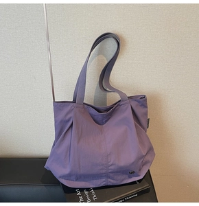 Detailed side view of purple nylon tote bag featuring shirred design and woven shoulder strap