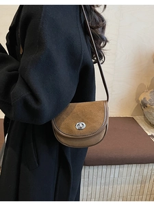 Close-up of vintage brown suede saddle bag with leather trim and silver metal lock