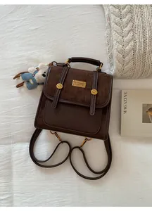 Detail of dark brown vintage backpack with suede texture and cute teddy bear charm