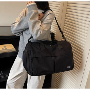 Detail of black nylon travel bag with large main compartment and side zipper pocket