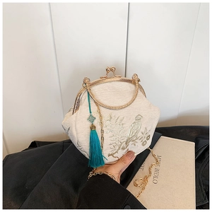 Detail of embroidered bird and floral pattern on cream shell bag with golden chain