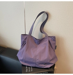 Detailed view of the purple tote bag fabric and woven brand label on side