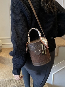 Brown quilted cylindrical bucket bag with silk scarf handle and golden lock pendants