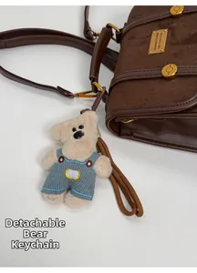 Detail of vintage brown bag with detachable plush bear charm and golden buckle hardware