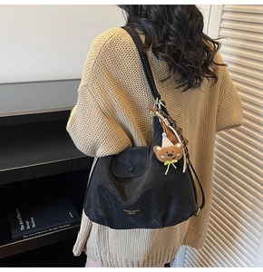Détail du sac cabas en cuir noir avec lettrage doré et charmant porte-clés d'ours peluche