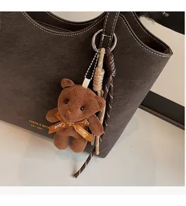 Gros plan sur un cabas en cuir grainé marron foncé avec un charmant ours en peluche