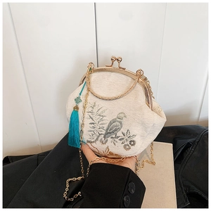 Detail of retro shell bag with delicate bird embroidery and golden chain strap