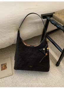 Detail of vintage matte black hobo bag with gold logo and wooden bead charm accessories