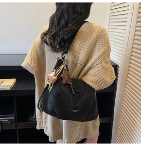 Détail d'un grand sac cabas en cuir noir avec charm ours et étoile porté par un mannequin